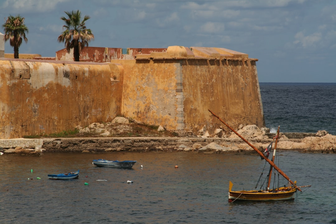 Photo by Dominique Josse brown boat on sea near brown concrete building during daytime